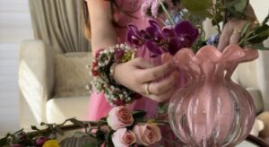 Foto de mão de criança mexendo em vaso de flores.
