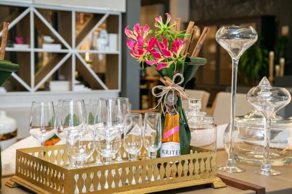 Espumantes harmonizam as combinações especiais com flores 1 Espumante Chandon dentro de cercado de madeira com taças e arranjo de Gloriosas.