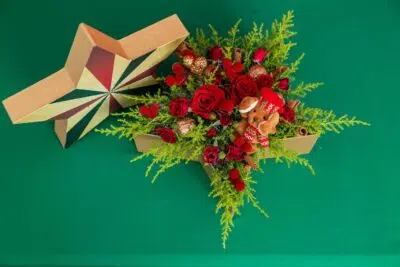 Símbolo da magia natalina: 3 Arranjos de Flores para o Natal 3 Buquê de rosas vermelhas em fundo verde ao lado de uma estrela vista de cima.
