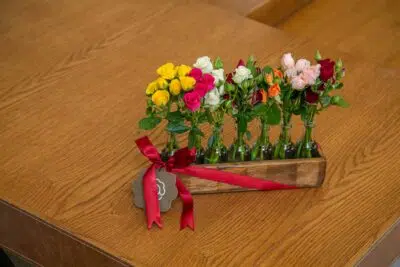 Presente para festa de formatura, conheça 5 flores e + 1 dica 3 Pequeno vaso de madeira contendo rosas coloridas: Amarela, rosa, branca, laranja, rosa-claro e vermelha.