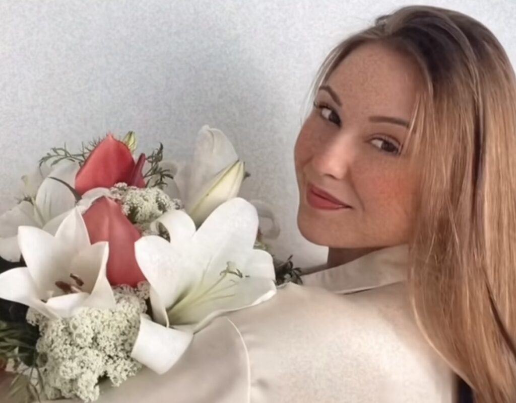 Mulher com buquê de flores de pétalas brancas e vermelhas para presentear no dia da mulher.