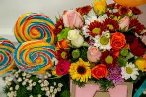 Arranjo de flores diversas com pirulitos para bebês.