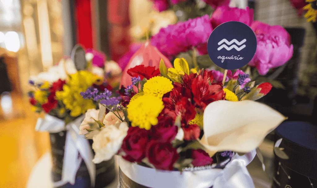 Buquê de flores variadas com placa com o símbolo do signo de aquário.