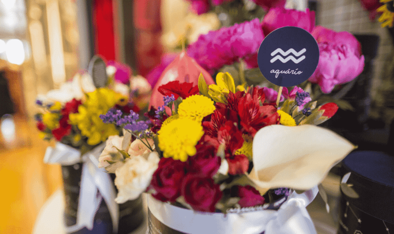 Buquê de flores variadas com placa com o símbolo do signo de aquário.